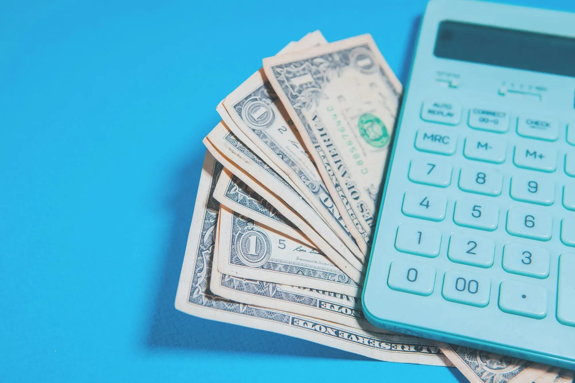 Billets de banque en éventail à côté d'une calculatrice turquoise