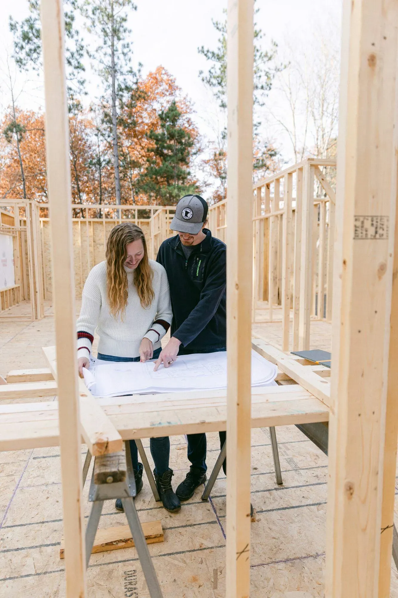 Couple consultant des plans de construction sur un chantier, projet de crédit immobilier