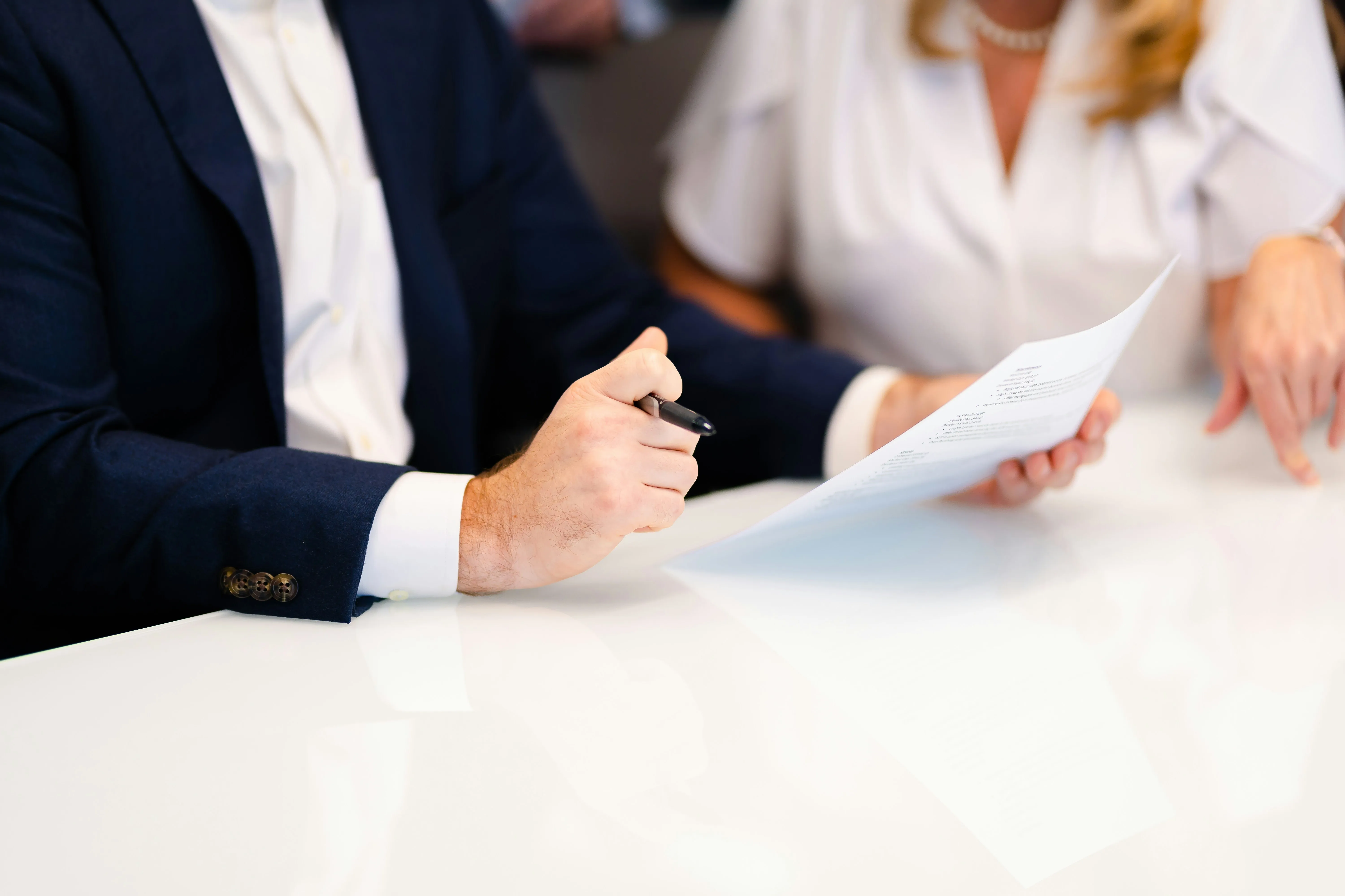 Homme et femme examinant un document au bureau, stylo en main