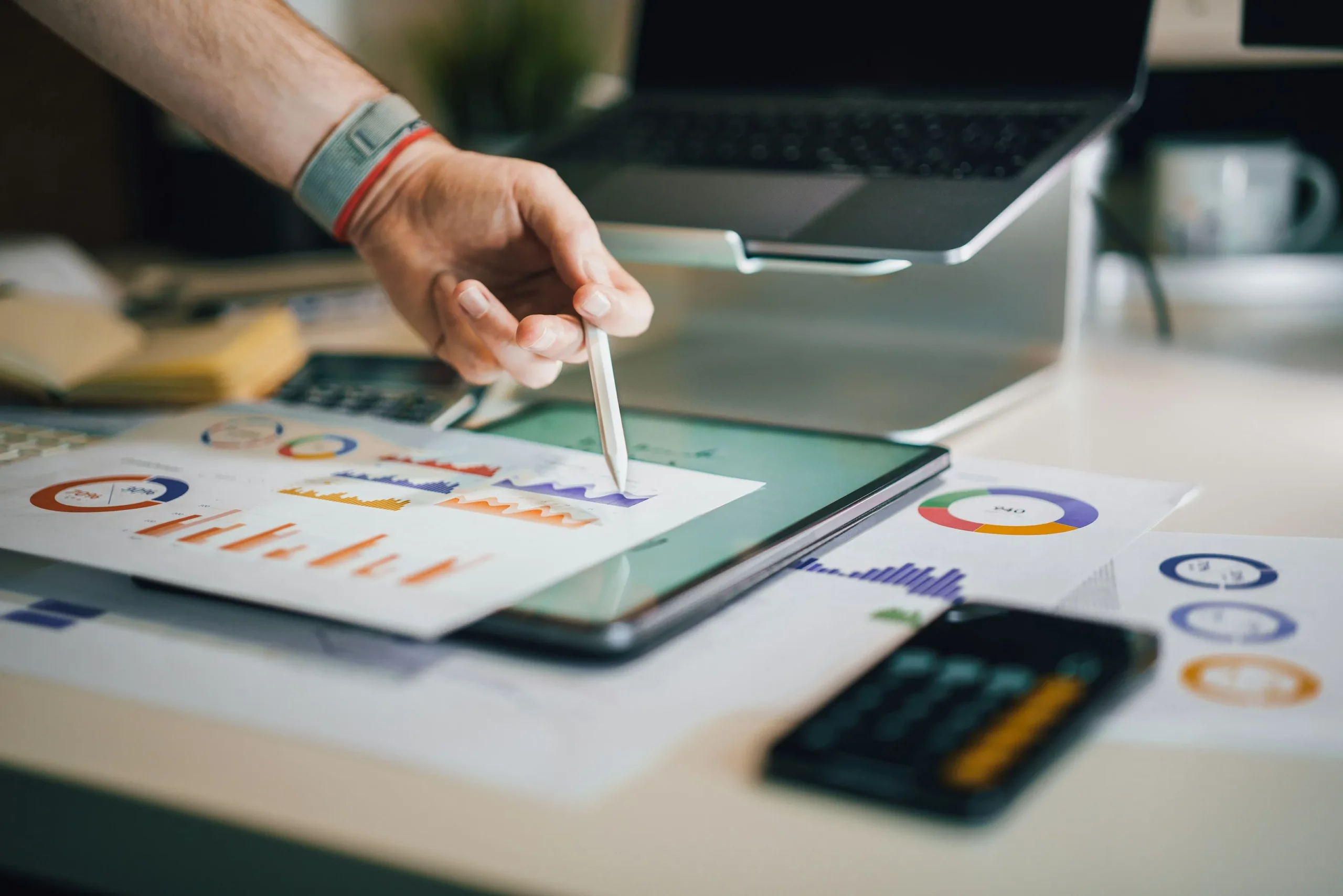 Main tenant un stylet au-dessus d'une tablette affichant des graphiques financiers