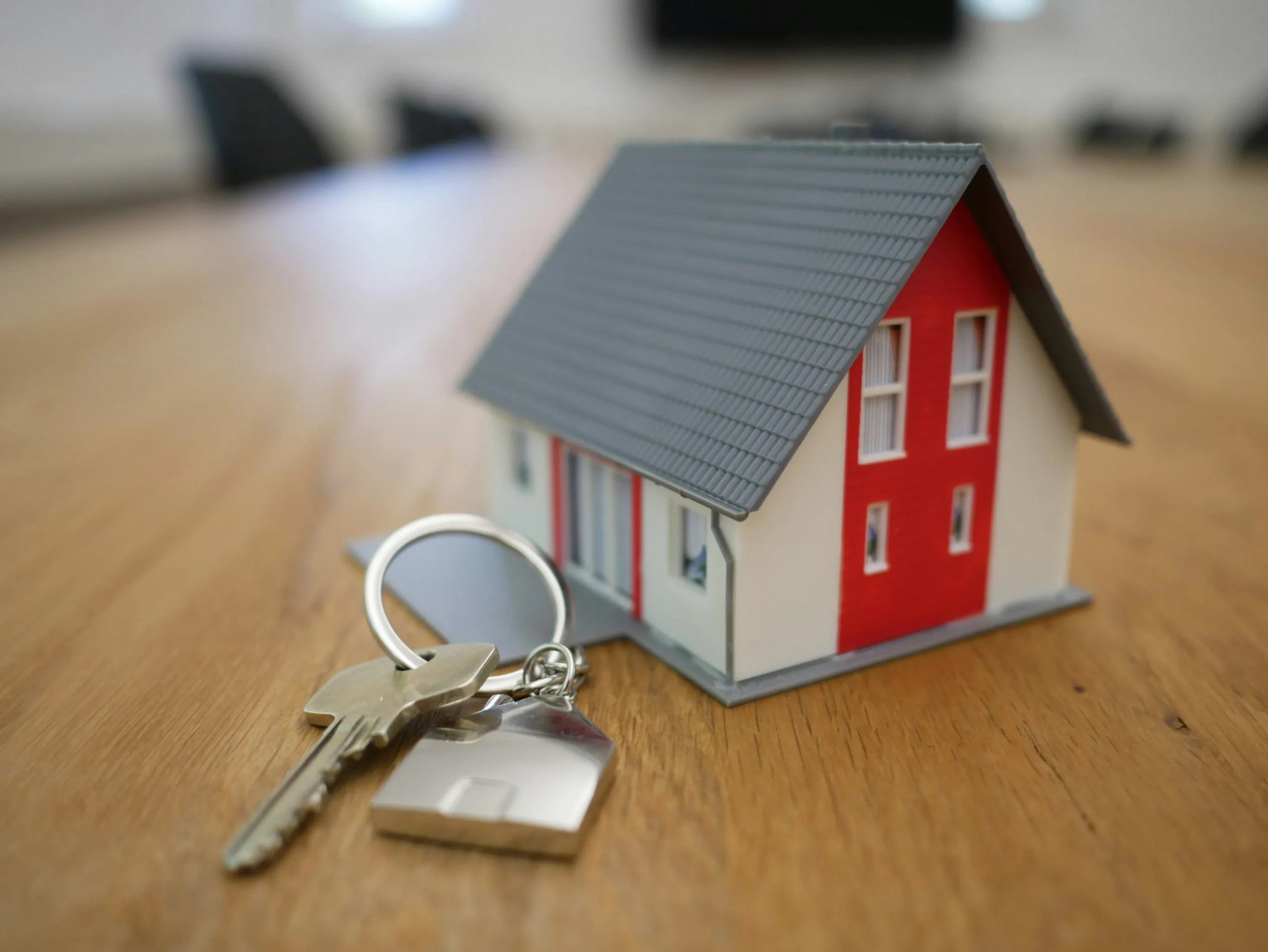 Maison miniature et trousseau de clés sur un bureau, symbole d'achat immobilier et de crédit