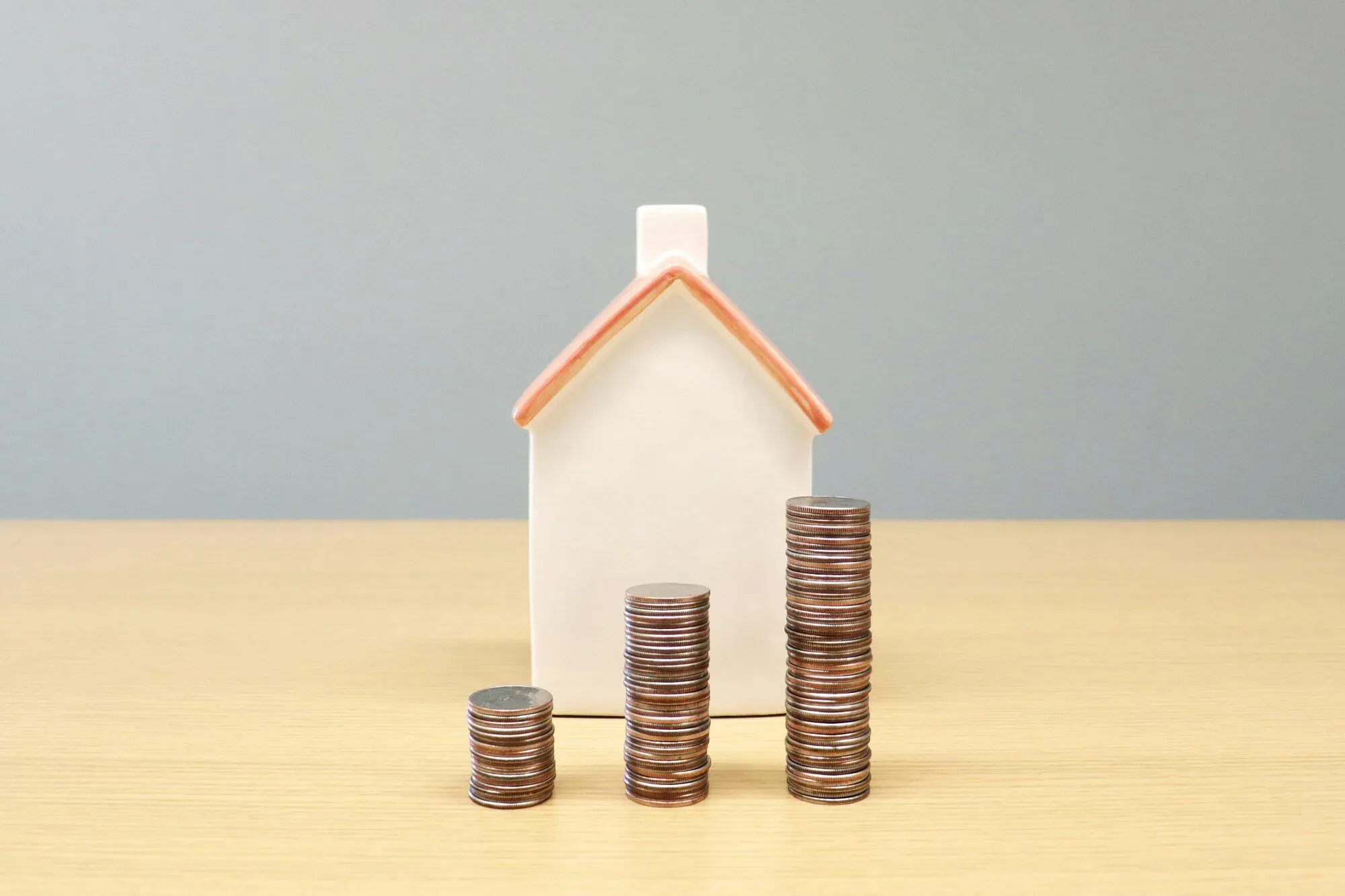 Maison miniature avec trois piles de pièces de monnaie croissantes