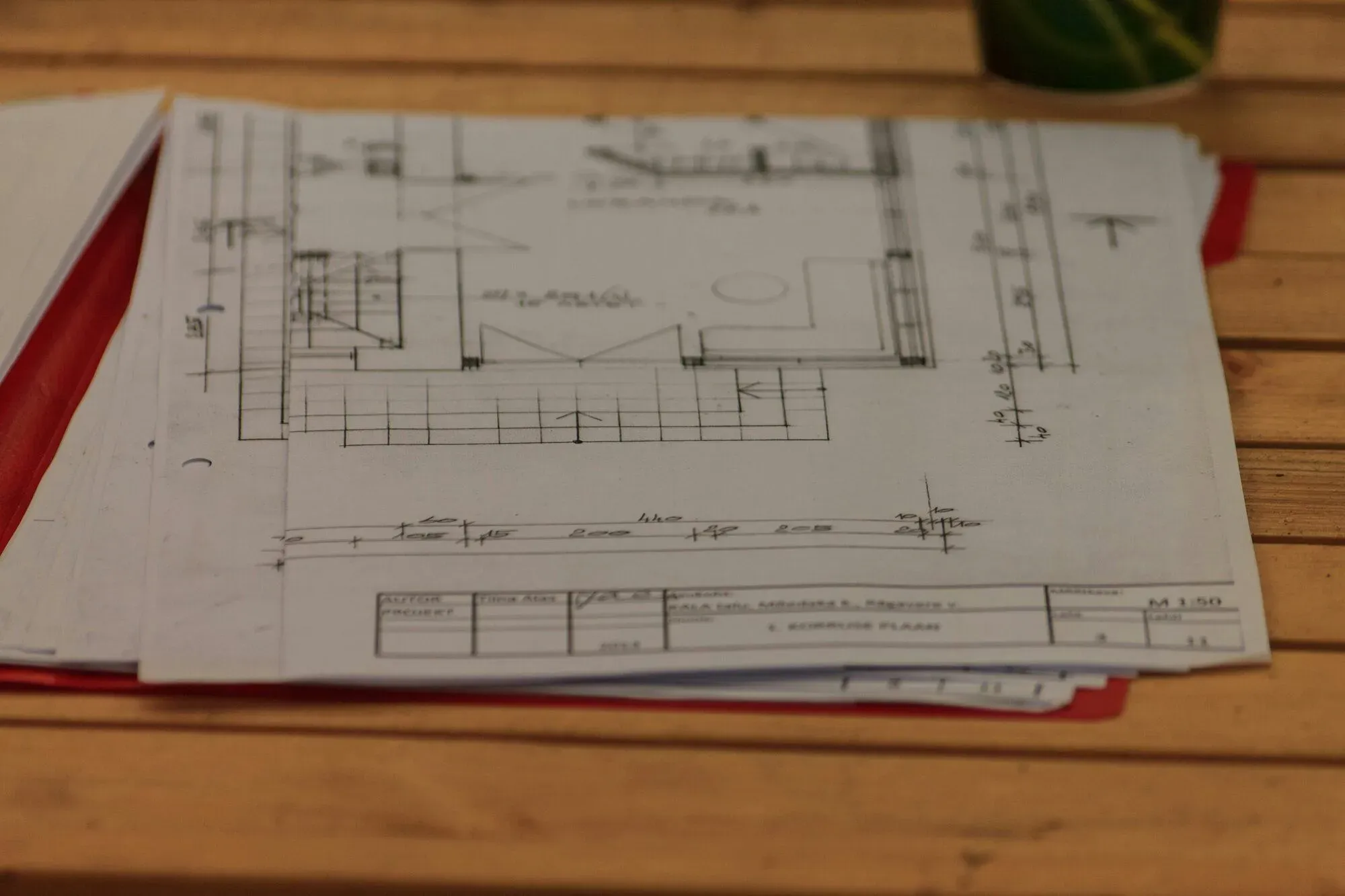 Plan d'architecte imprimé posé sur une table en bois